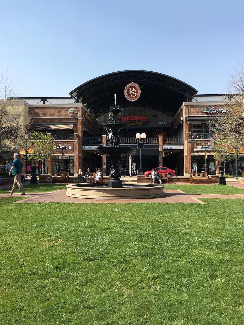 Historic shopping center with fountain and retail stores in a vibrant outdoor mall setting.