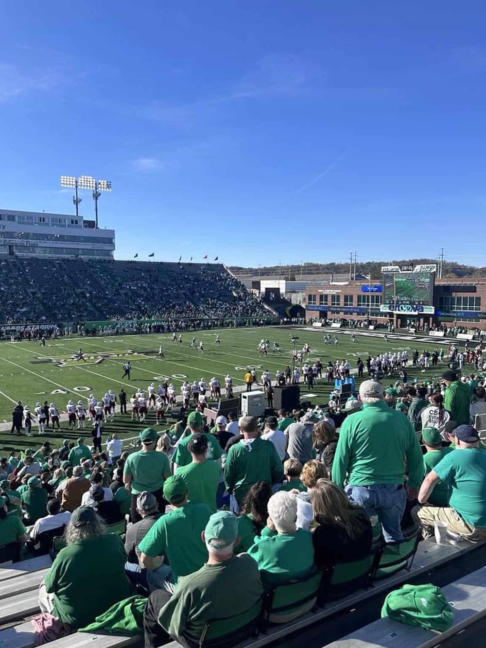 Vibrant football game at QuestForDirections stadium with enthusiastic fans and sunny weather.