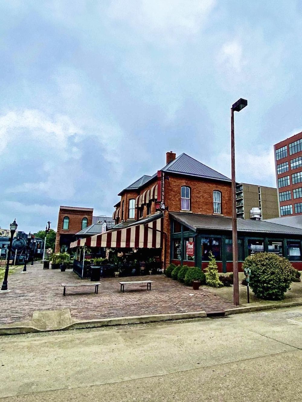 Charming brick restaurant with outdoor seating, historic architecture, and vibrant greenery in downtown area.