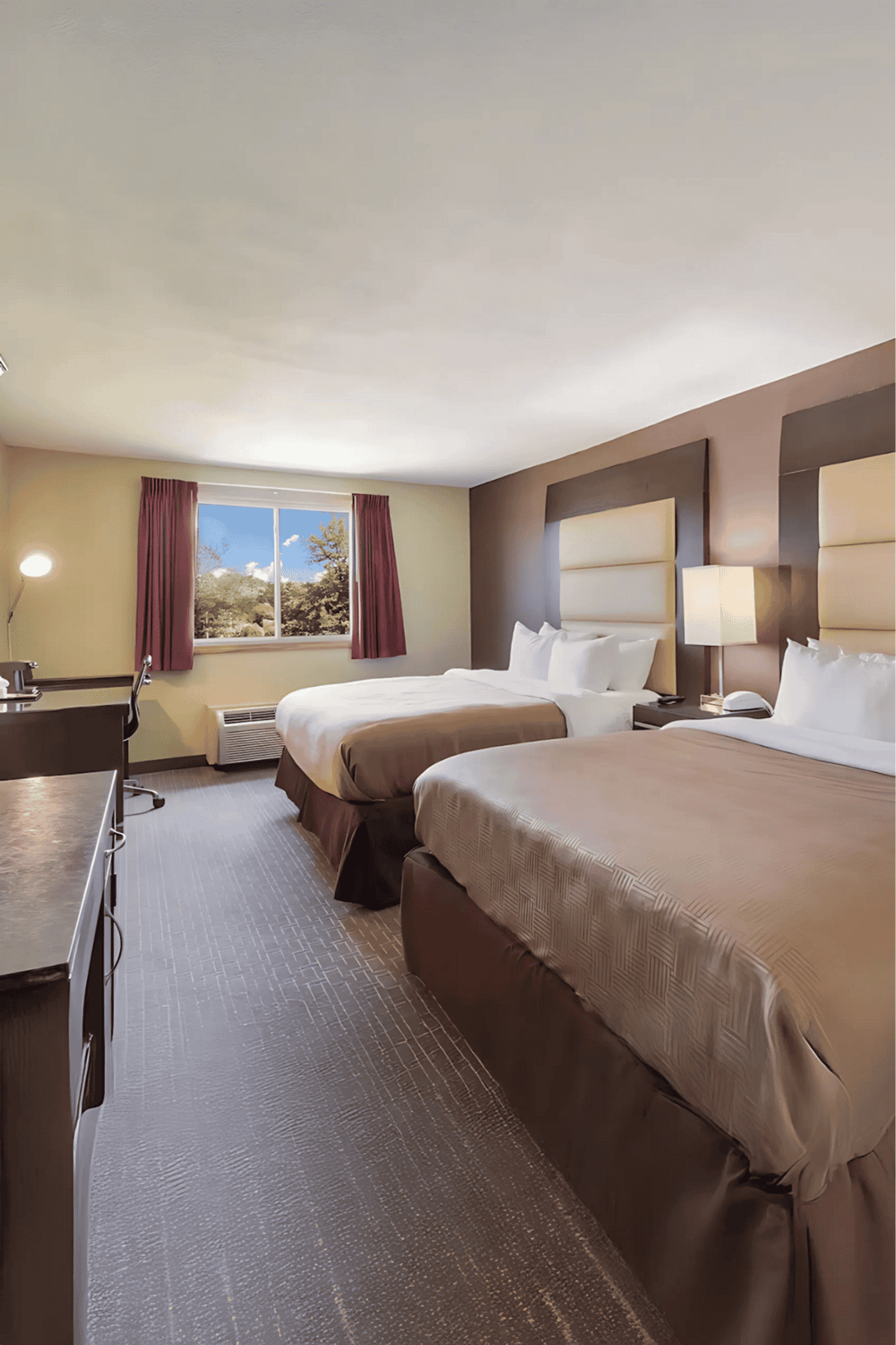 Comfortable hotel room with two beds, modern decor, and scenic window view. Ideal for travelers seeking relaxing accommodations.