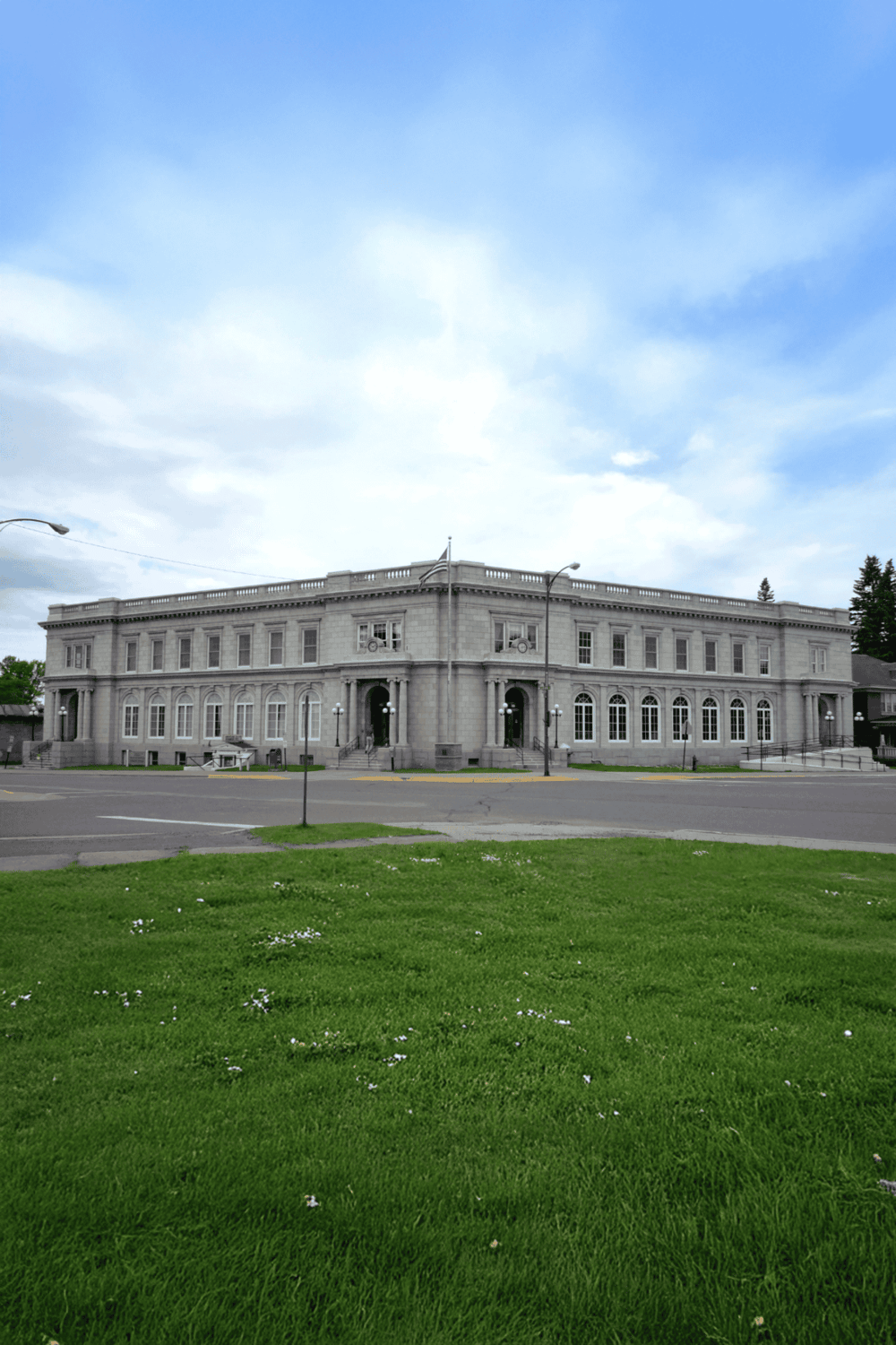 Historic government building with classical architecture and large windows, located in a lush green area.