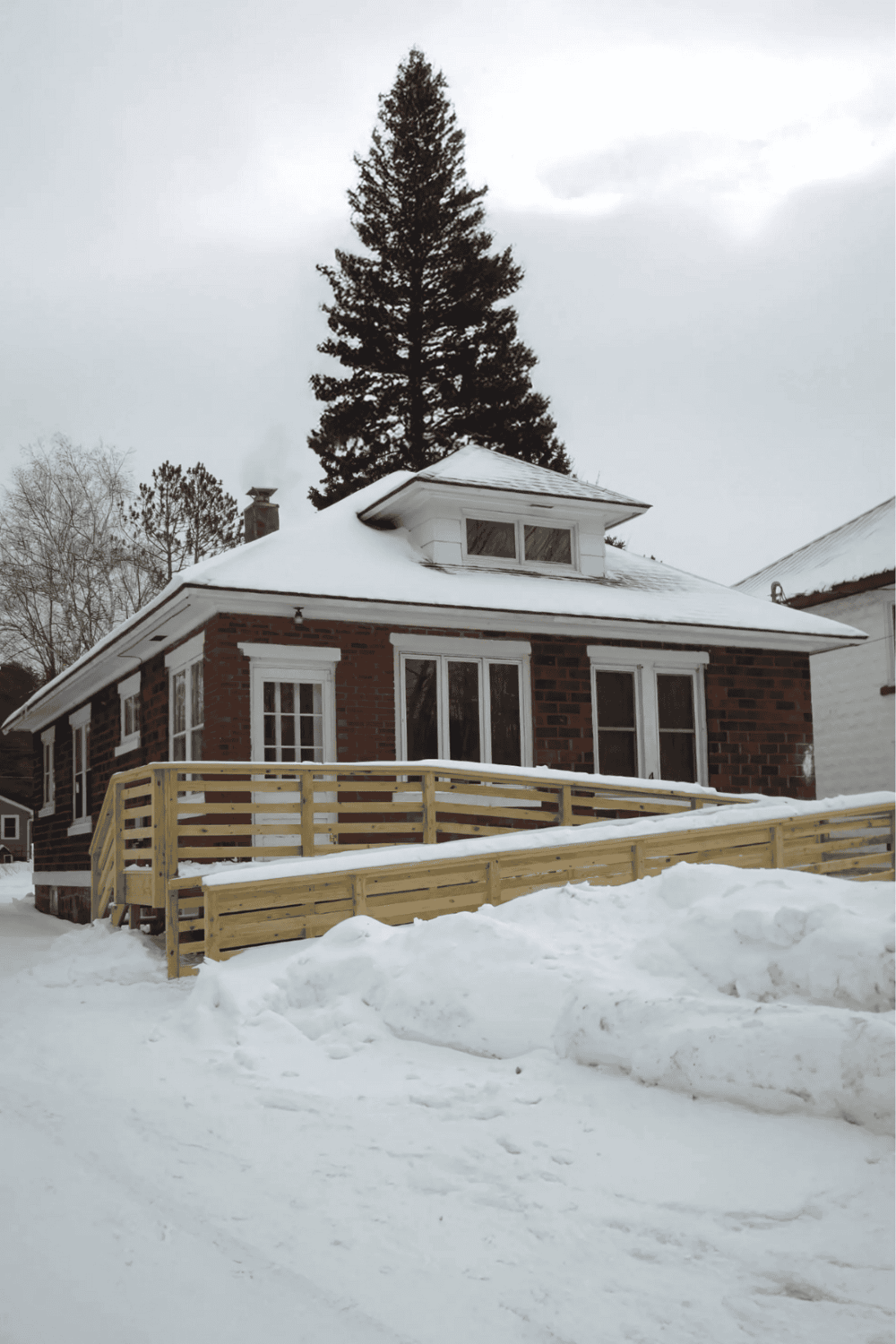 1. Cozy brick house with snow-covered roof and wooden ramp in winter scene.