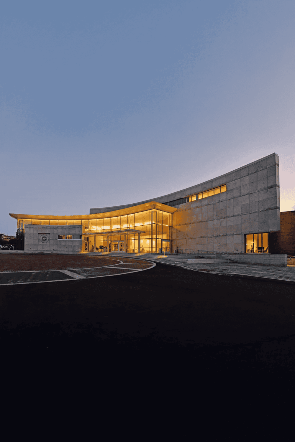 Modern hospital building with illuminated entrance at dusk, showcasing healthcare and medical facility excellence.