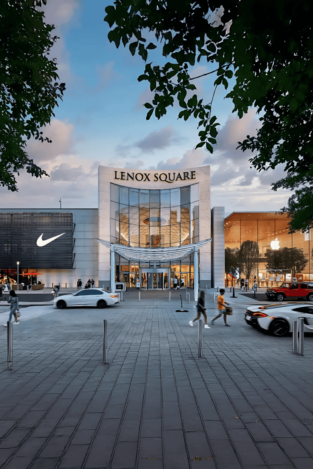 LENOX SQUARE shopping mall exterior with storefronts of Nike and Apple, busy parking lot, modern retail architecture, evening ambiance.