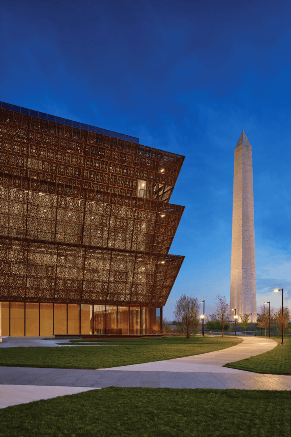 Modern museum exterior with intricate facade design and Washington Monument in background.
