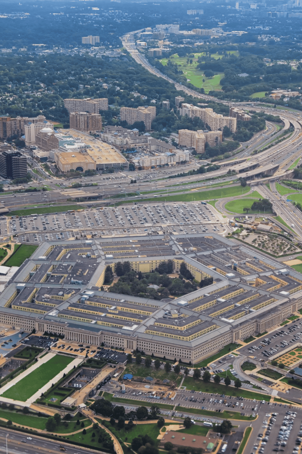 Modern aerial view of a large government or institutional complex with surrounding highways and cityscape, emphasizing navigation and directional services.