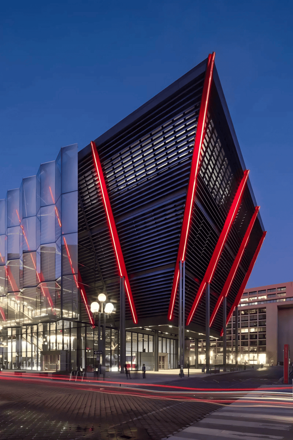 Futuristic modern building with red LED accents, illuminated at dusk, showcasing innovative architecture.