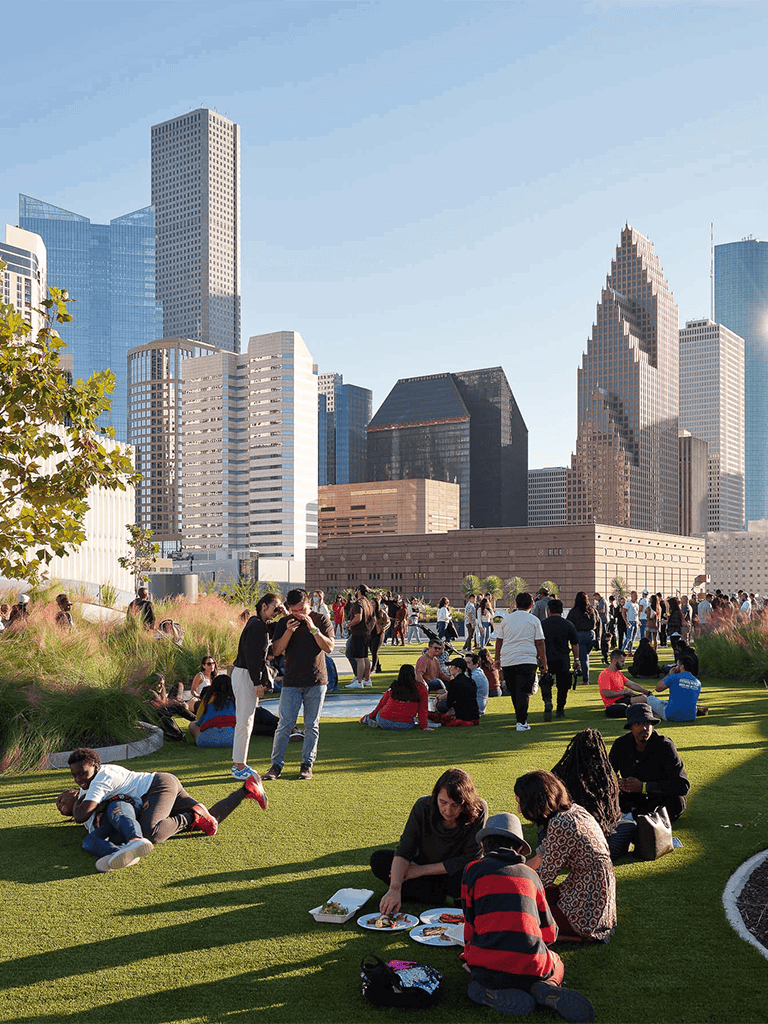People enjoying outdoor activities at Discovery Green park in downtown Houston, Texas.