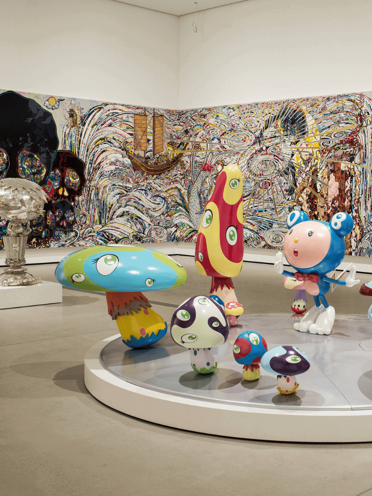Colorful whimsical mushroom and character art sculptures in an indoor gallery.