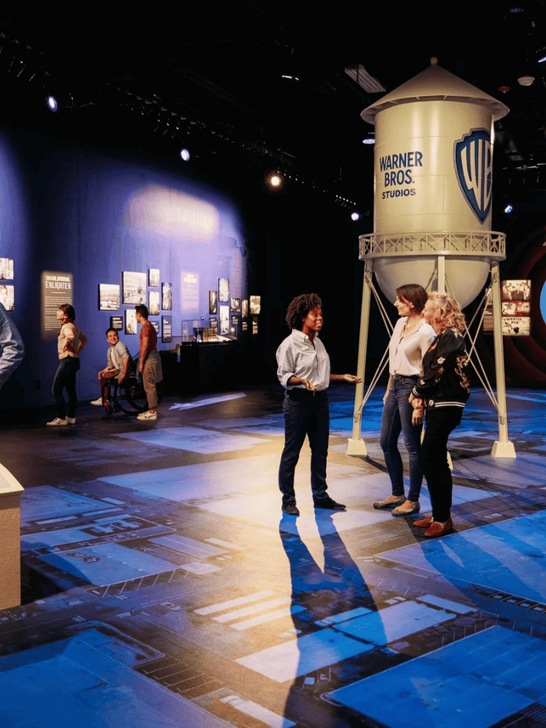 Warner Bros Studios tour exhibit with visitors exploring iconic movie memorabilia.