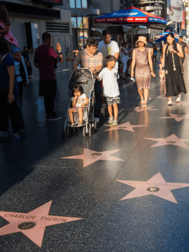 Child walking on Hollywood Walk of Fame stars, family exploring famous celebrity sidewalk.