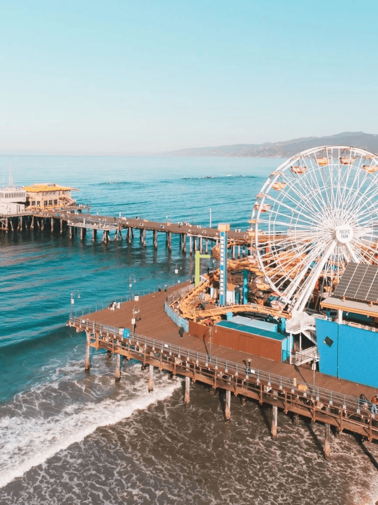 Brightly colored Santa Monica pier with a Ferris wheel overlooking the ocean.