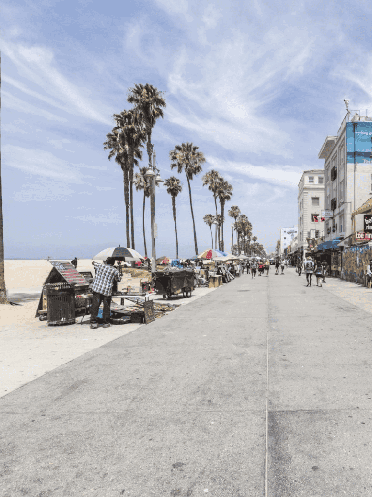 Surfside beach walk with vendor stalls and palm trees on a sunny day.