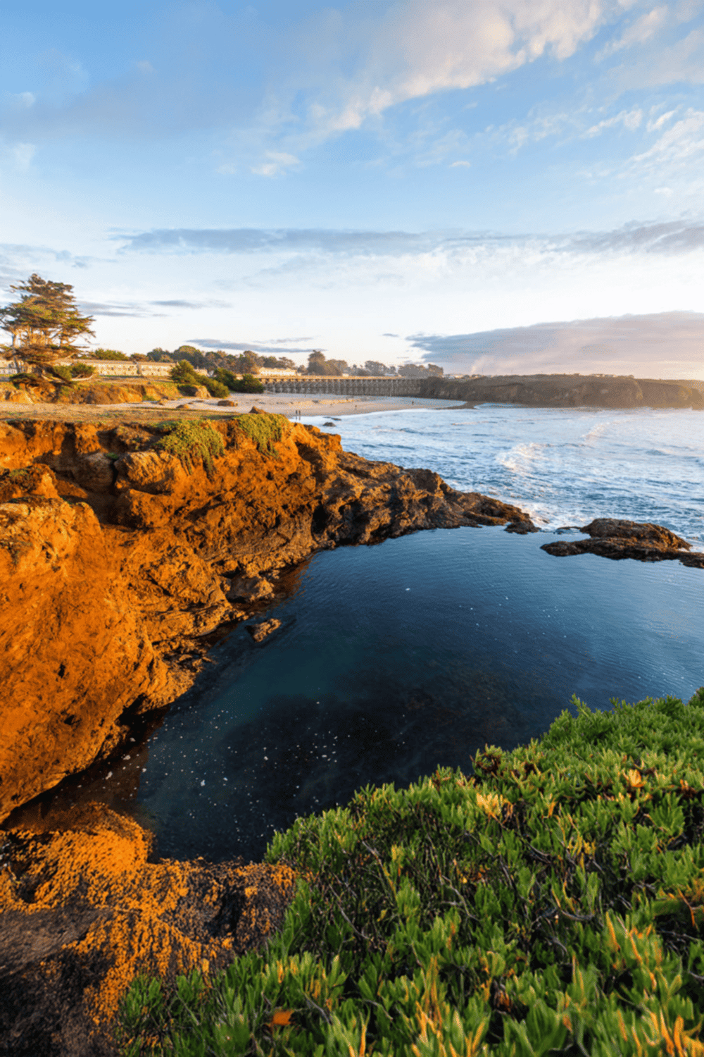 Secluded coastal hot spring pool with ocean view at sunset, scenic California shoreline.