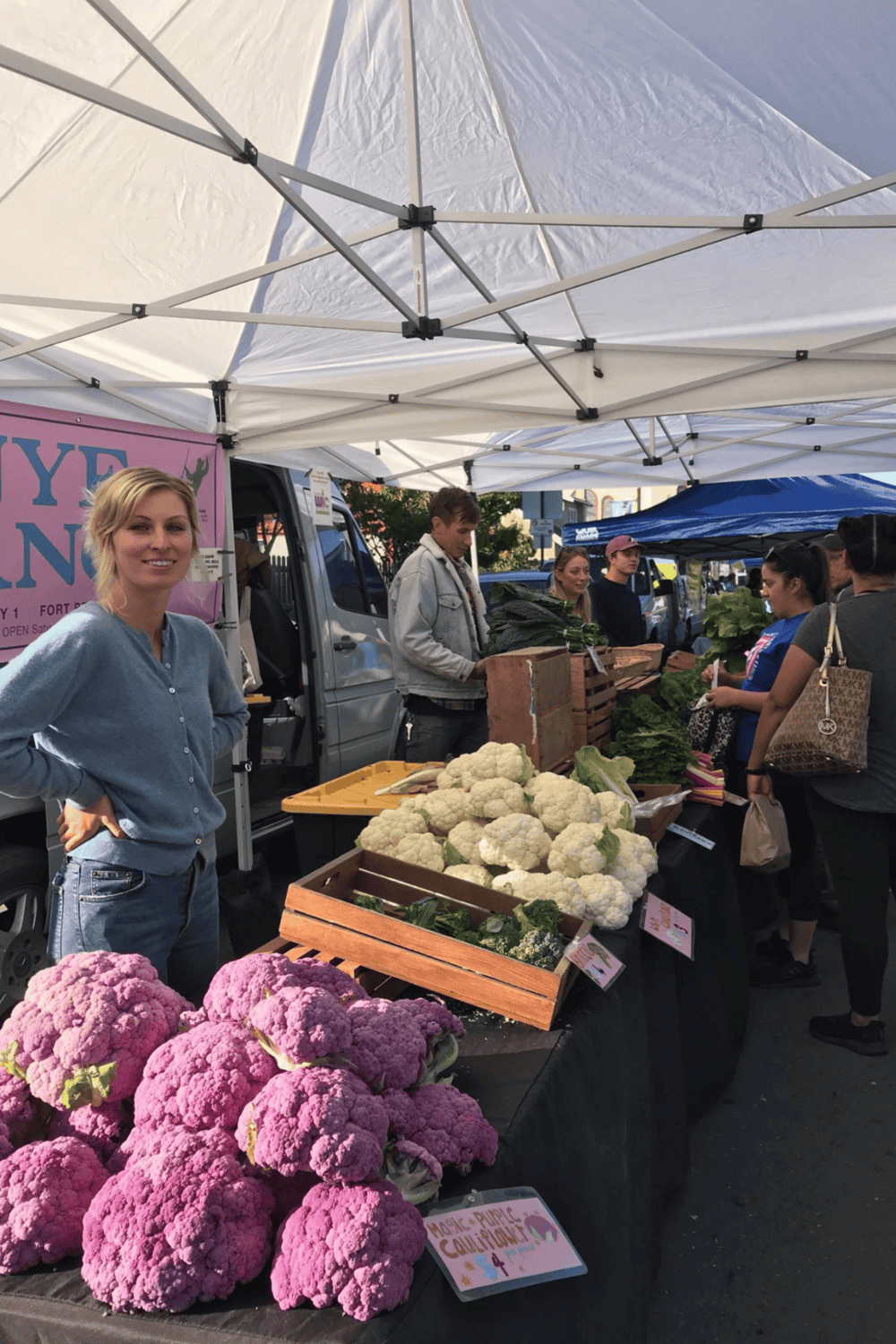 Fresh produce at a local farmers market offering colorful cauliflower and other vegetables for sale.