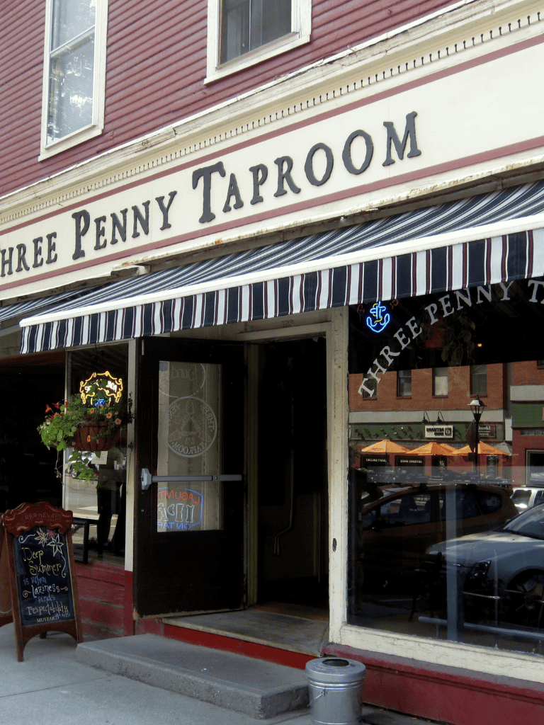 Three Penny Taproom outdoor restaurant entrance, cozy historic pub with striped awning in a small town.