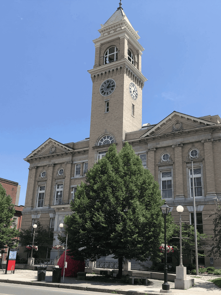 Historic courthouse with clock tower, downtown architecture, and green trees.
