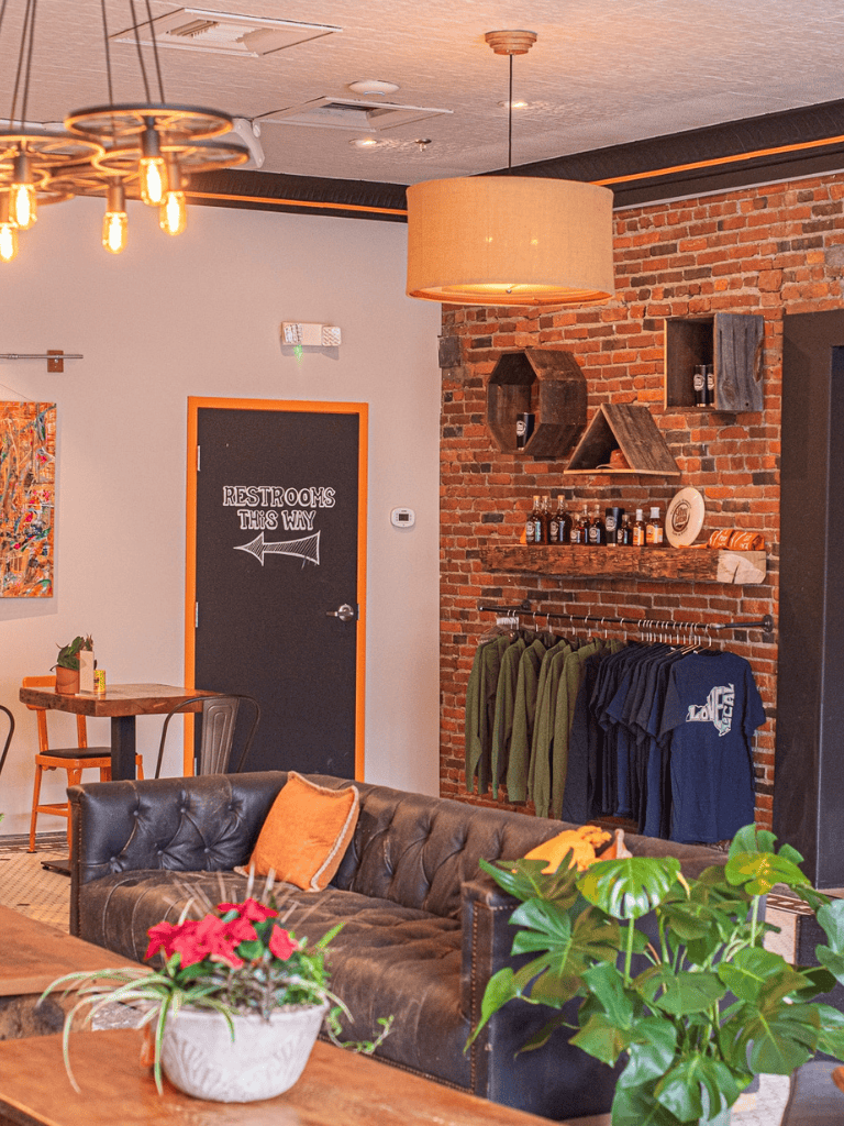 Charming indoor café with brick walls, cozy seating, and retail apparel area, perfect for relaxed customer experiences.