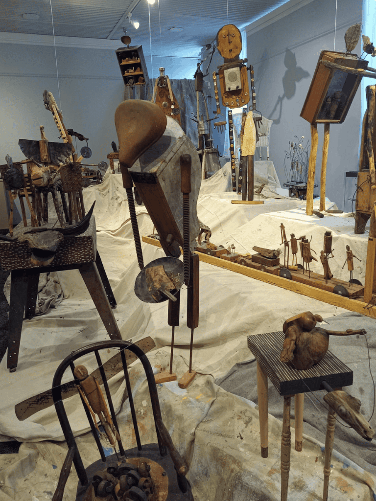 Rustic artistic sculptures and antique tools displayed in a creative art exhibition.