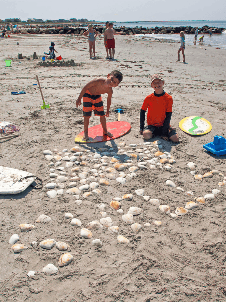 Colorful surfboards and seashells on sandy beach, kids enjoying beach day and beach activities.
