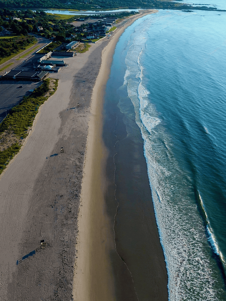 Seaside beach with waves and coastal development, aerial view.
