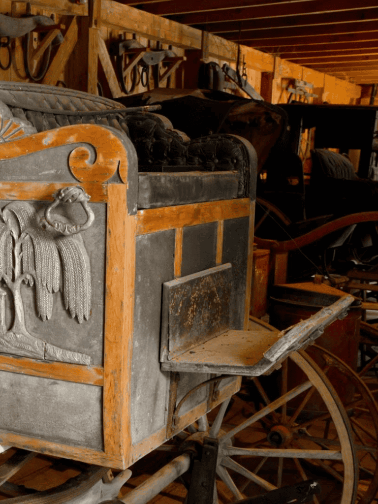 Antique wooden horse-drawn carriage in rustic barn setting for preservation or display.