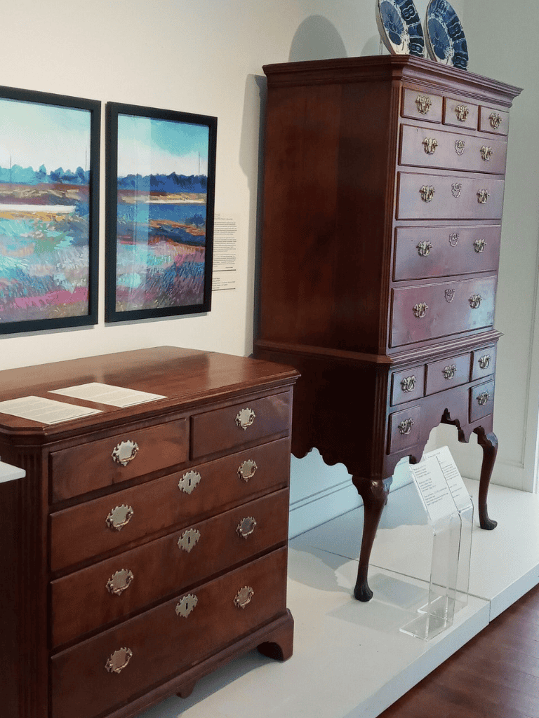 Intricate antique wooden dressers on display in a museum exhibit, showcasing historical furniture craftsmanship.