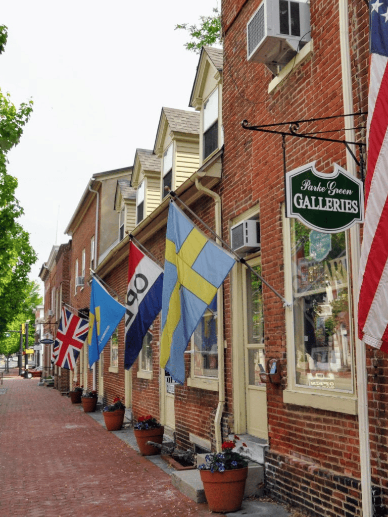 Colorful flags and brick storefront at Gallerie arts district with trees in background.