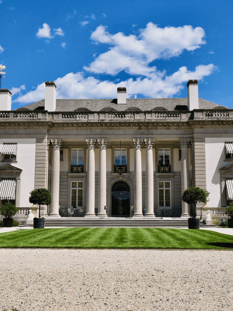 Elegant mansion with grand columns and lush landscaping in a scenic setting.