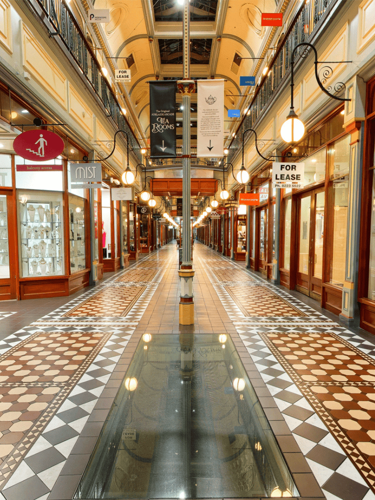 Balcony access sign and shopping mall corridor with "for lease" signs and ornate tile flooring.