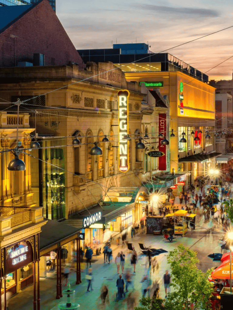 Regent Street shopping district at dusk with vibrant store signs and busy crowd.