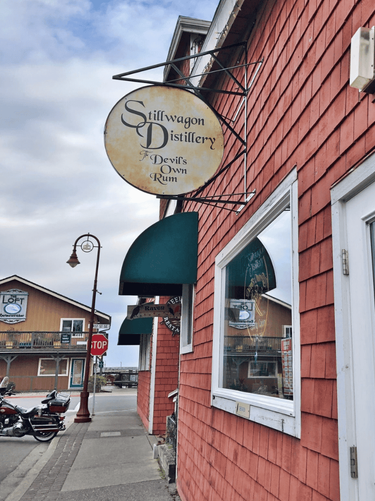 Rustic Stillwagon Distillery sign, historic downtown building, and waterfront view.