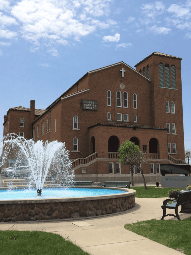 Historic Baptist church with brick architecture and water fountain in downtown area.