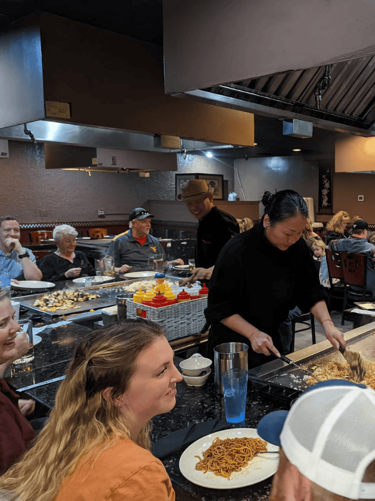 Delicious Japanese cuisine being prepared and enjoyed at a bustling restaurant with happy diners.