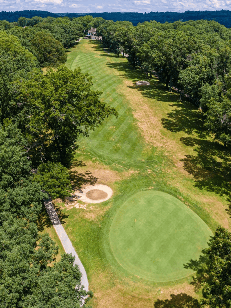 Lush golf course with green fairways and surrounding trees, perfect for an outdoor golf experience.