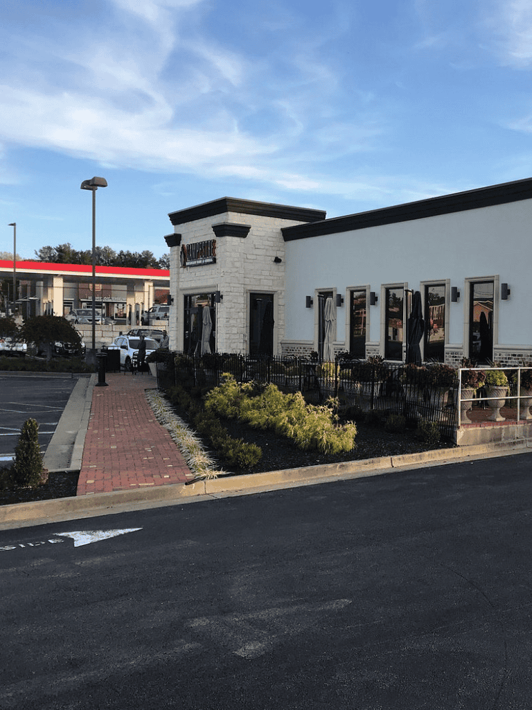 Modern restaurant exterior with outdoor patio and landscaping, offering dining options in a welcoming atmosphere.