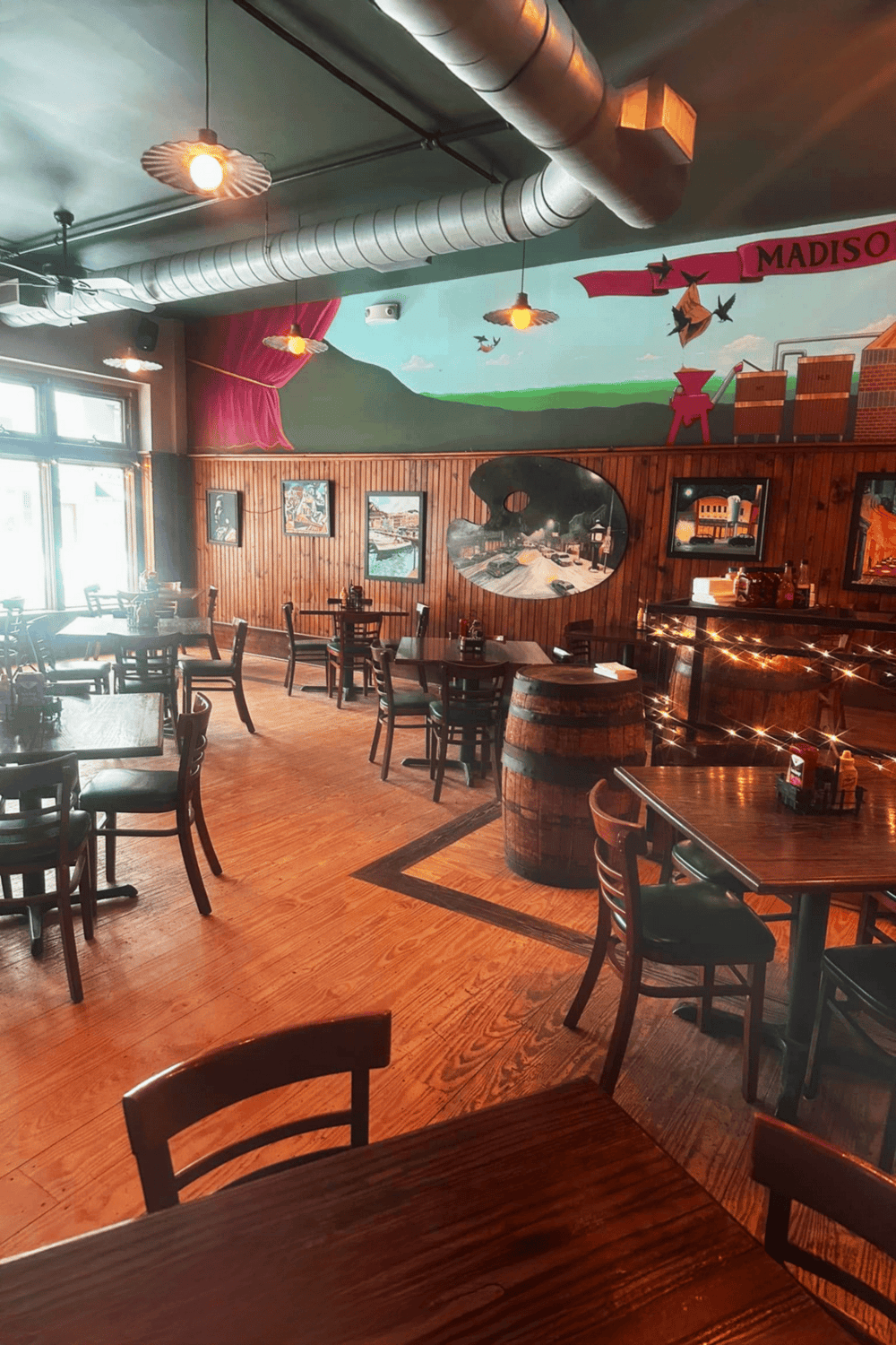 Cozy restaurant interior with wooden tables and chairs, colorful mural, and warm lighting.