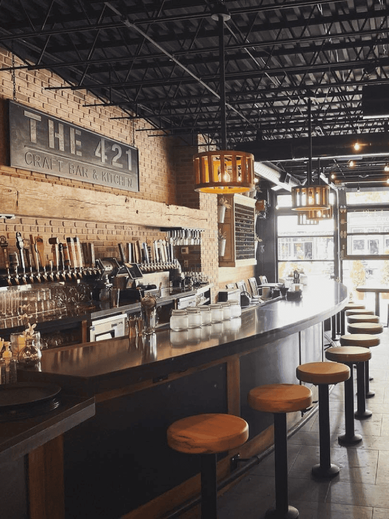 Craft bar and kitchen interior with brick walls, wood accents, and modern lighting, perfect for a cozy dining experience.