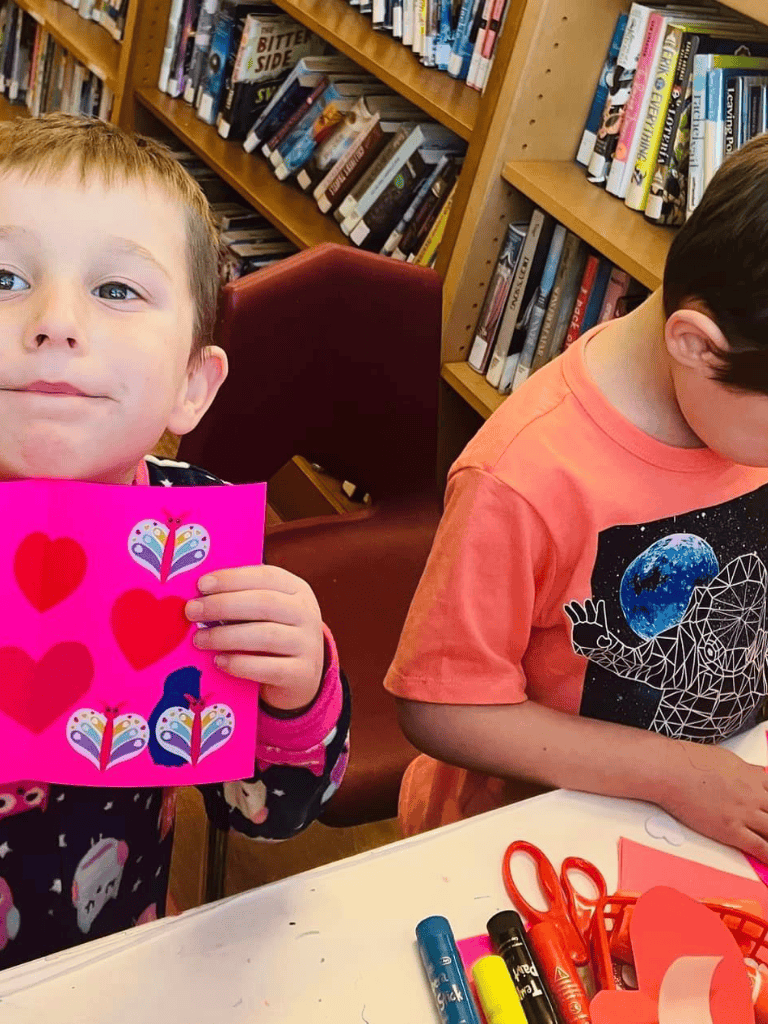 Colorful Valentine's Day craft with children in library, showcasing creativity and learning.