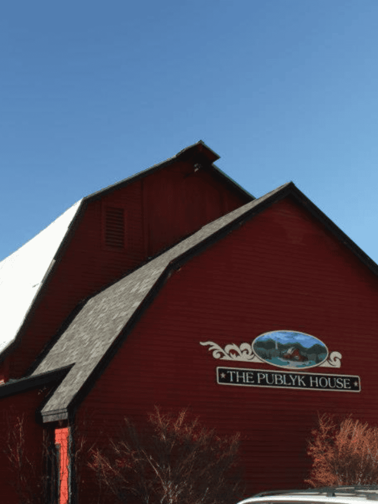 Colorful red church building with "The Publyk House" sign, set against a clear blue sky in Wisconsin.