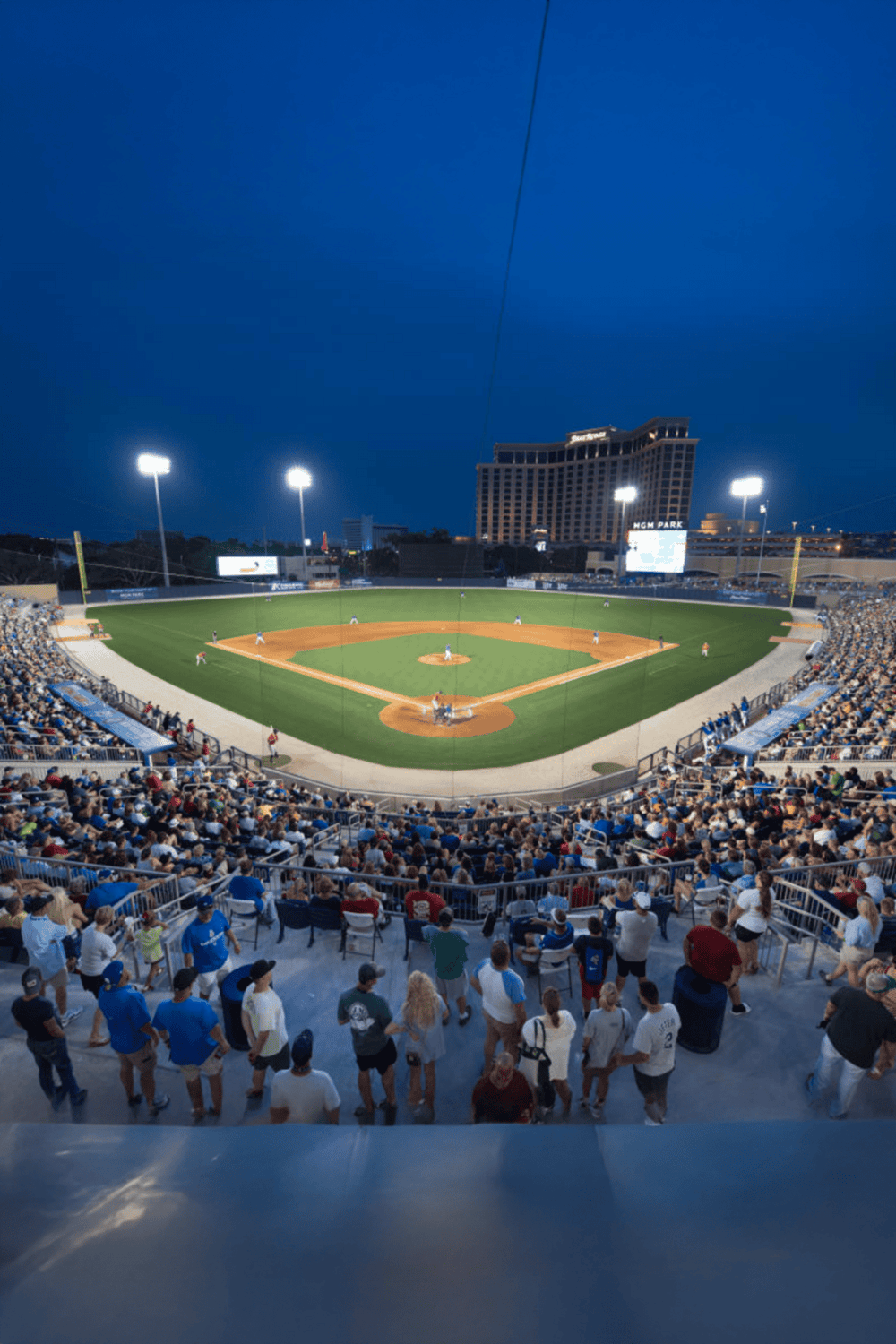 Battery-powered illuminated outdoor baseball stadium at night, crowds watching game.