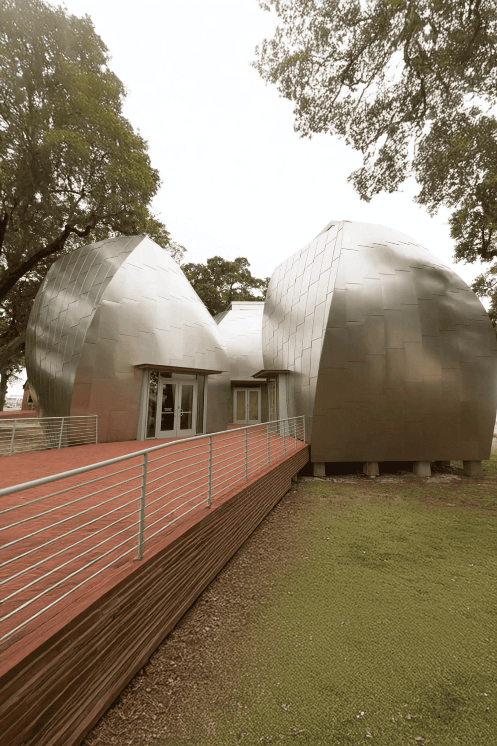 Modern architectural building with metal exterior and unique curved design, surrounded by trees.