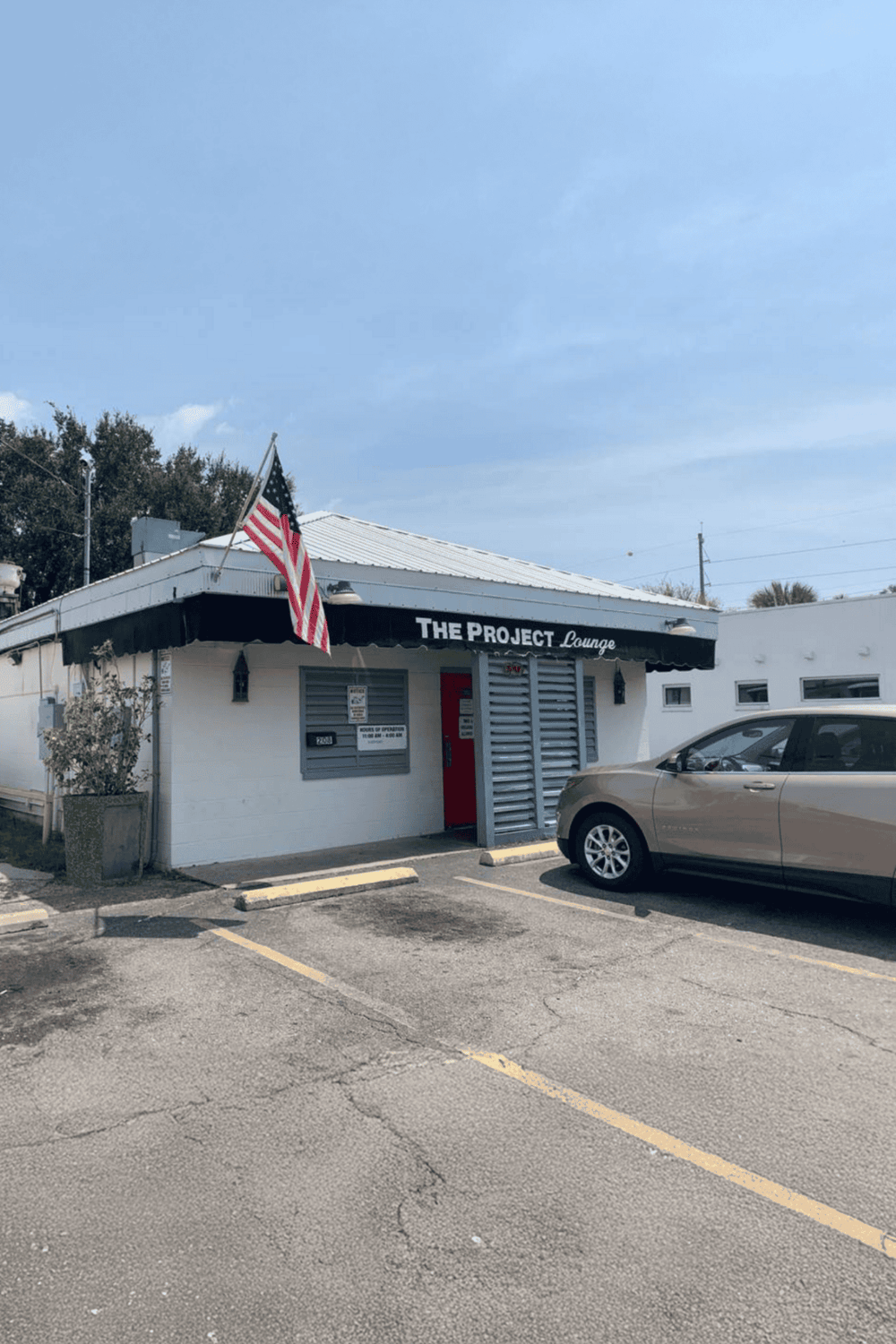 American flag outside The Project Lounge, a cozy local spot for relaxation and socializing.