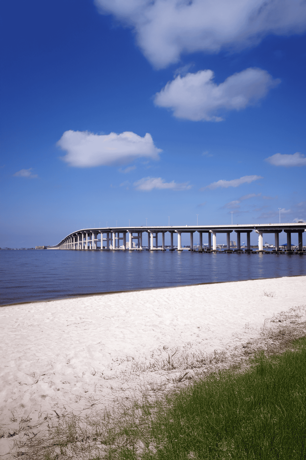 Bridge over water with blue sky and clouds, scenic coastal location, sunset view, modern structure, travel, sightseeing, adventure.
