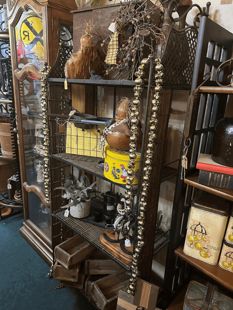 Vintage decorative iron shelving unit with eclectic collectibles and rustic accents.