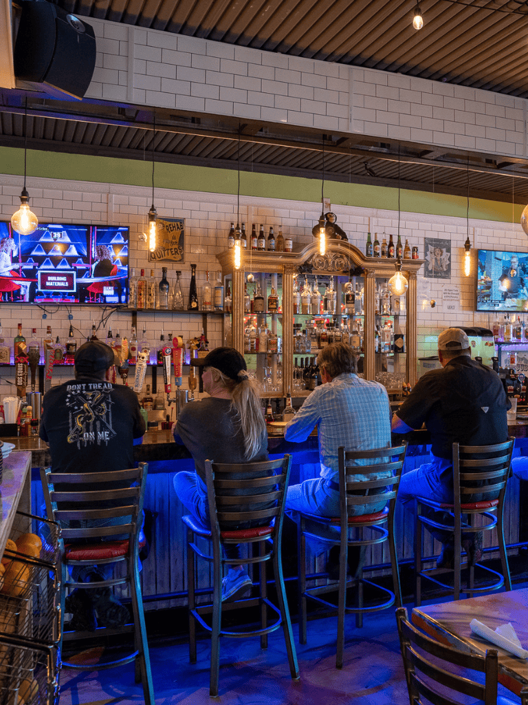 A bar scene with patrons enjoying drinks in a modern, lively restaurant setting.