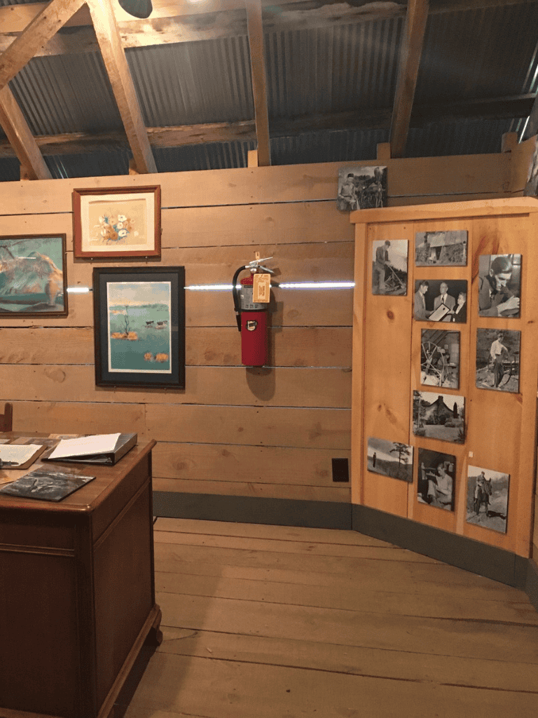 Aerial photography of rustic wooden gallery interior with vintage artwork and black-and-white photos display.