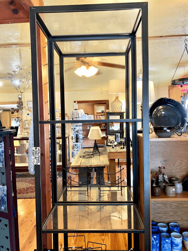 Antique metal display rack in a home decor store, showcasing rustic and vintage furniture and accessories.