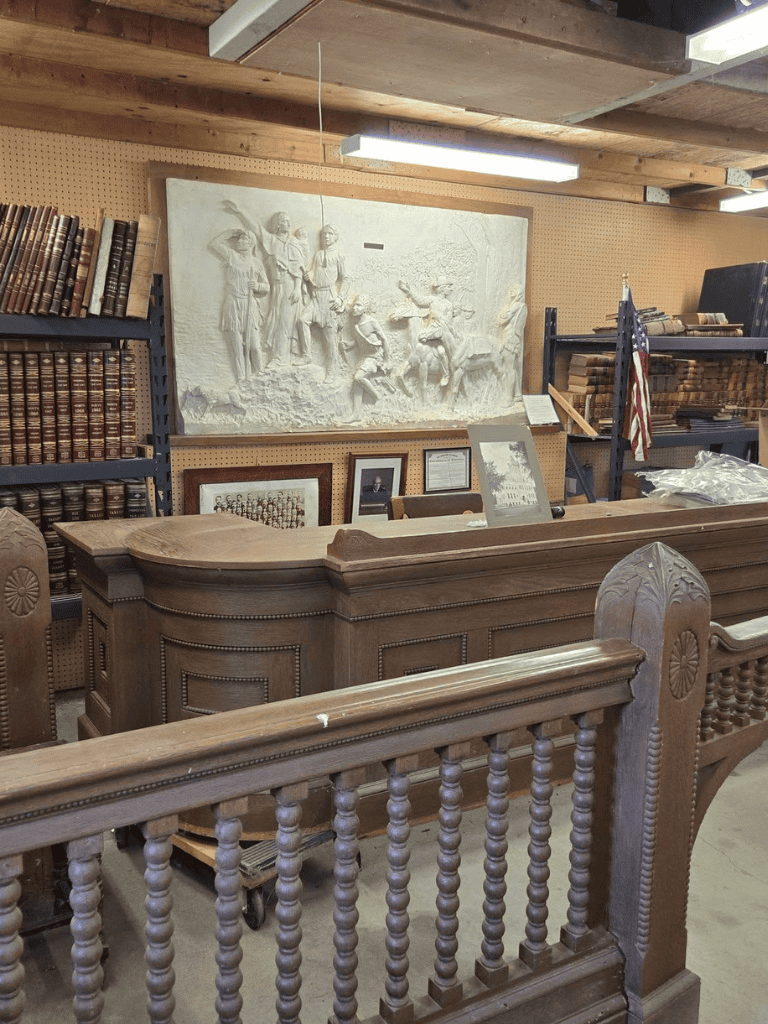 Antique wooden courtroom desk with historical artifacts in a museum setting.