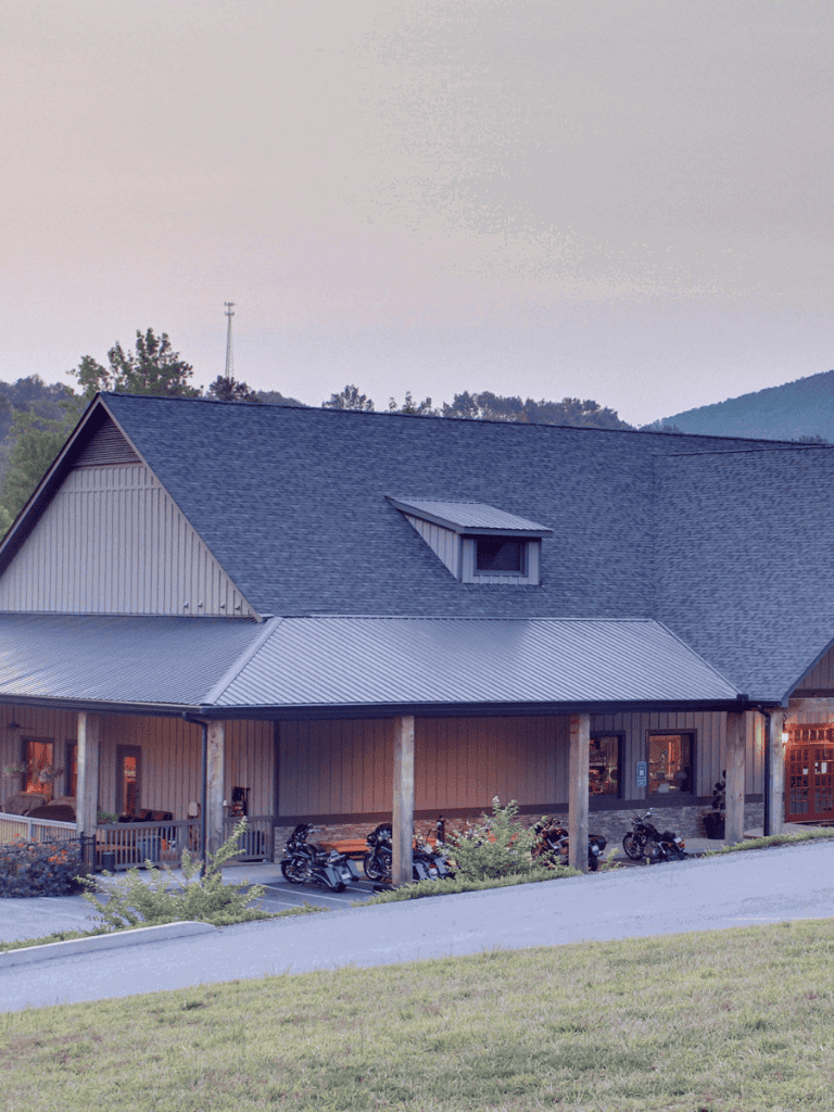 1. Modern rustic barn-style building with motorcycles parked outside, scenic mountain backdrop.
